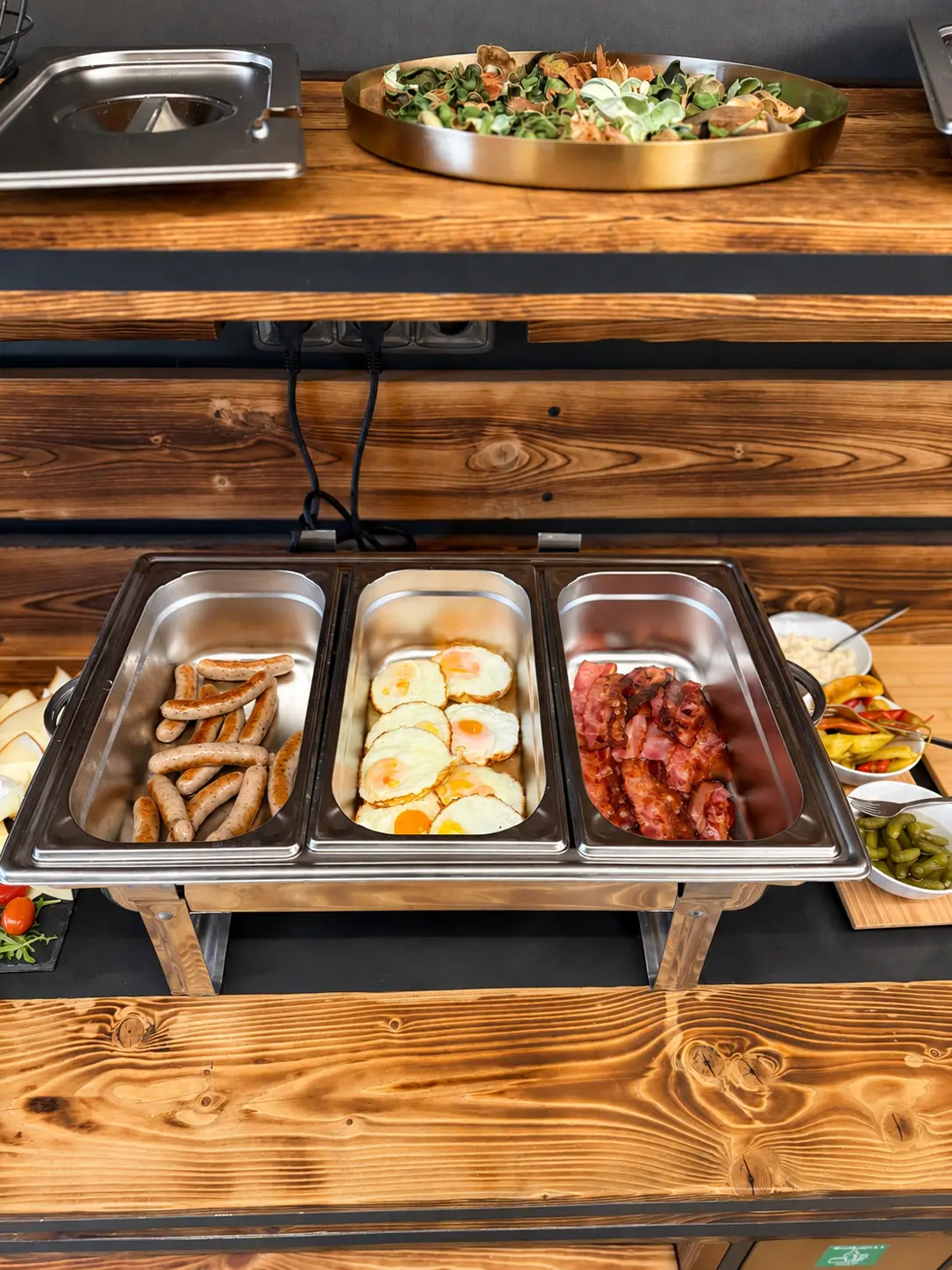 Breakfast buffet — sausages, eggs and bacon in chafing dishes