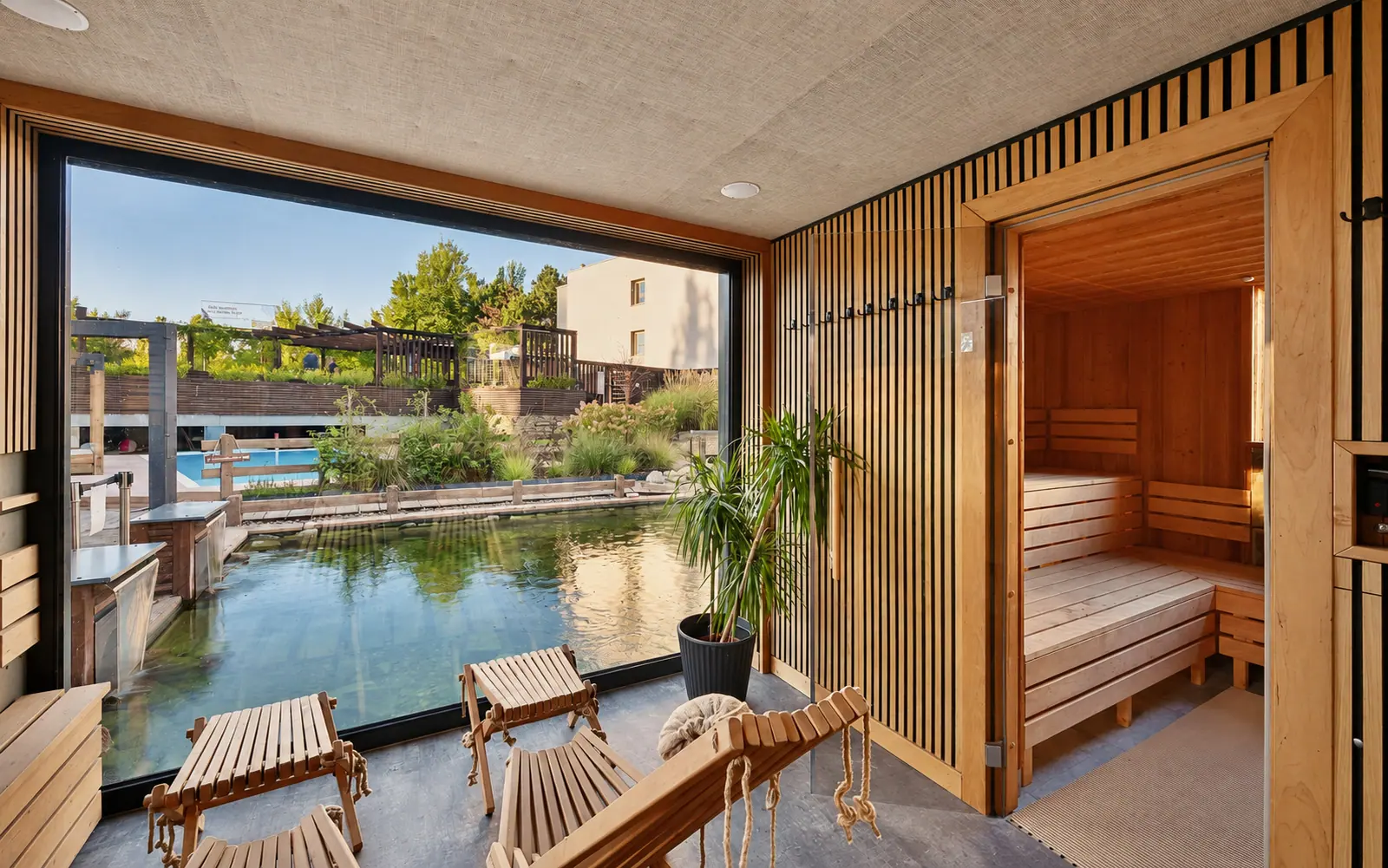 The lounge, with a sofa, wooden tables and a glazed wall onto the garden