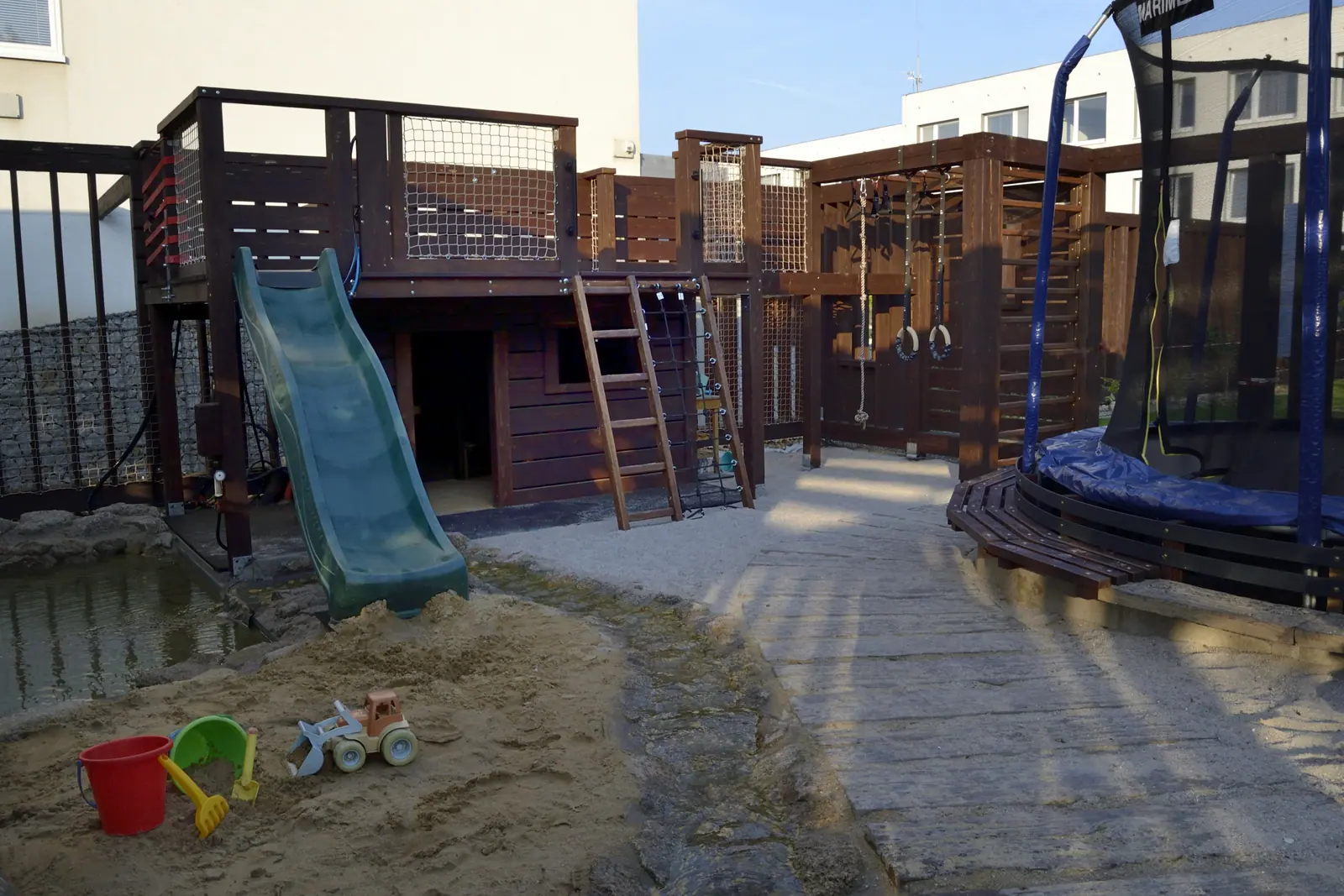 The playground, with a slide, a trampoline and a sandpit